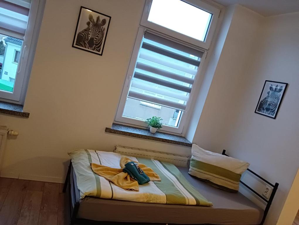 een klein bed in een kamer met 2 ramen bij Stella's Monteurswohnungen in Crimmitschau
