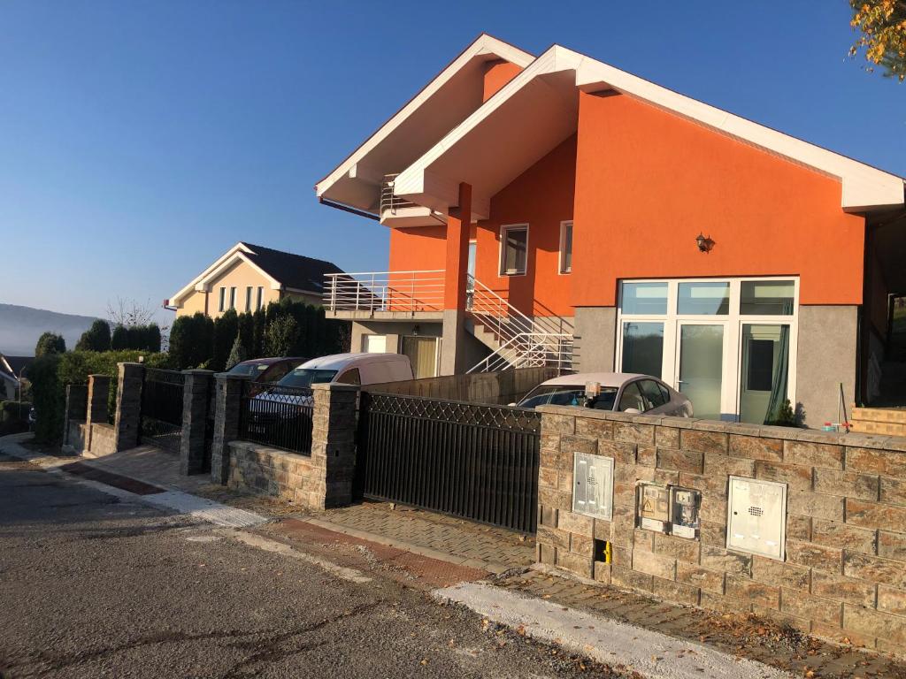una casa naranja con una valla delante de ella en Orizont-Livezeni en Livezeni