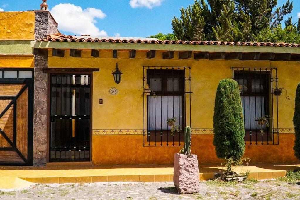 a yellow house with three windows and a cactus at Casa Margarita , La fuente de la luna in Tequisquiapan