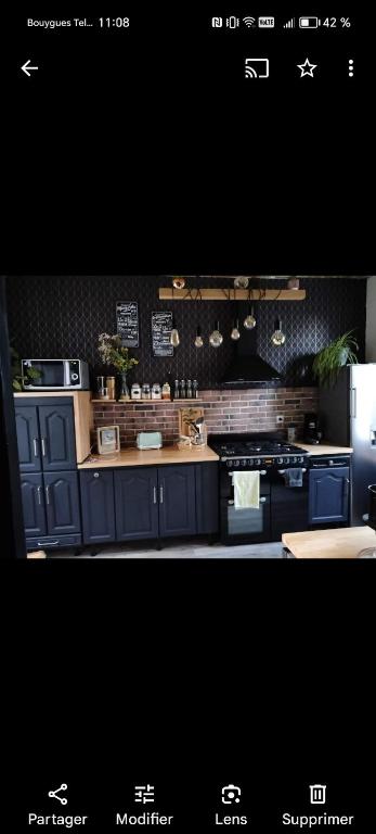 - une cuisine avec des placards bleus et une cuisinière dans l'établissement Maison papillon, à Fougères