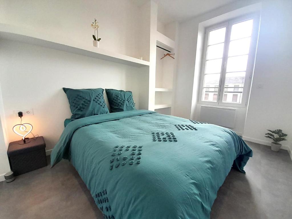 une chambre avec un lit avec une couette bleue et une fenêtre dans l'établissement le bugatti T2 en face de la gare, à Châteauroux