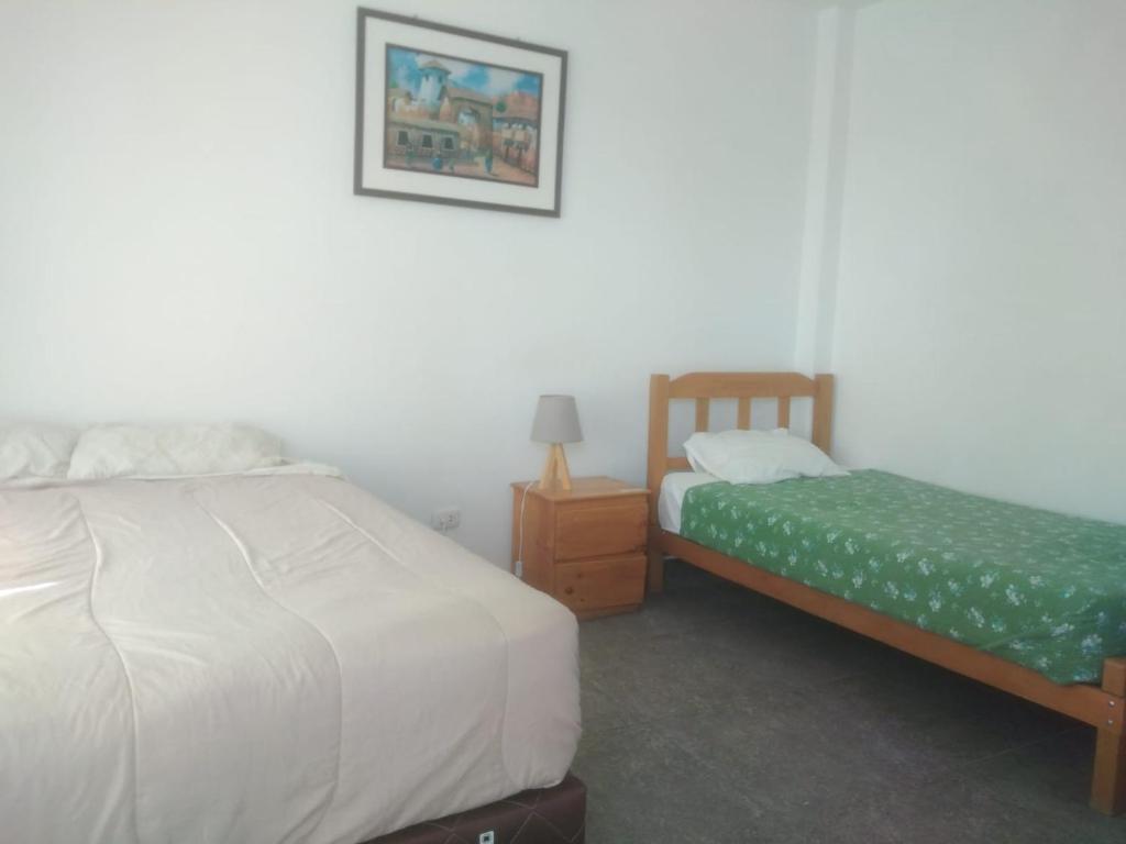 una camera con due letti e un comodino di HOSPEDAJE PARACAS SUR a Paracas