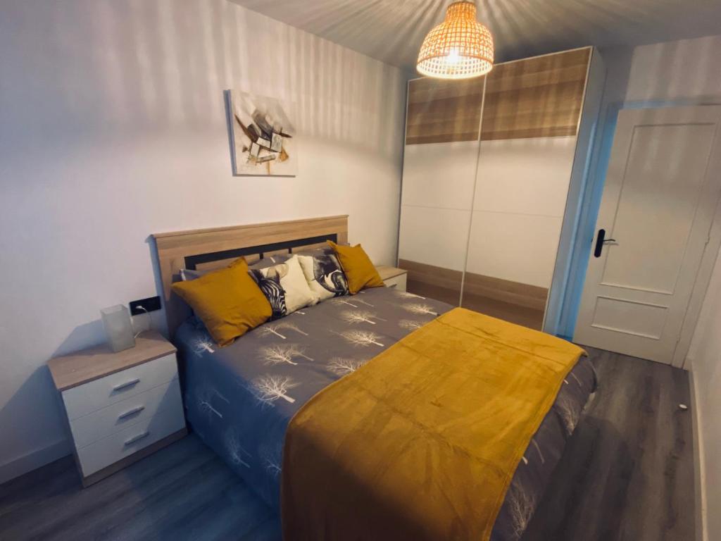 1 dormitorio con 1 cama con almohadas amarillas en Apartamento Centro NOVORT, en Gijón