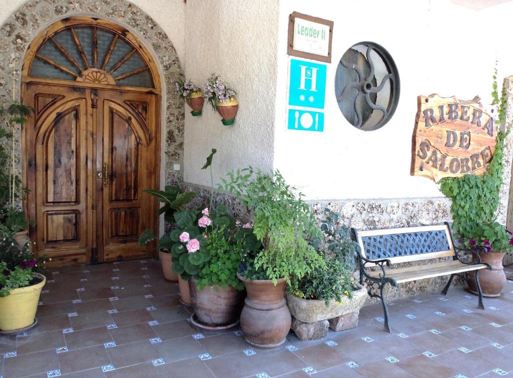 a bench in front of a door with potted plants at Hostal Ribera de Salobre in Salobre