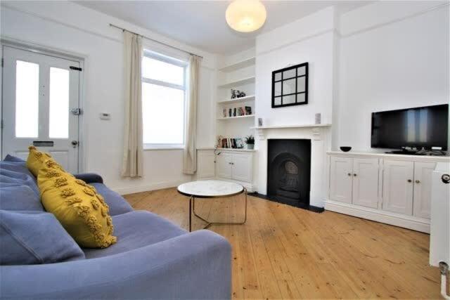 a living room with a blue couch and a fireplace at Cosy 2 bedroom Victorian townhouse in the town Centre in Bury Saint Edmunds