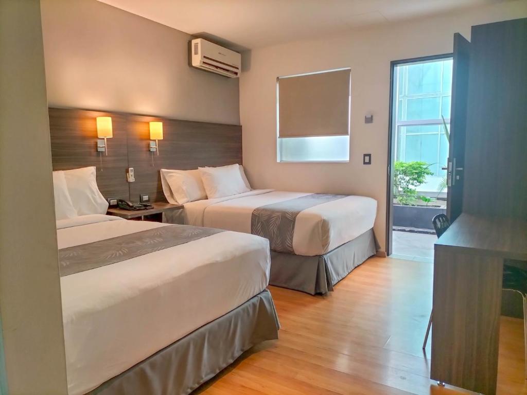 a hotel room with two beds and a window at El Hotel Business Class - Zamora Centro in Zamora de Hidalgo