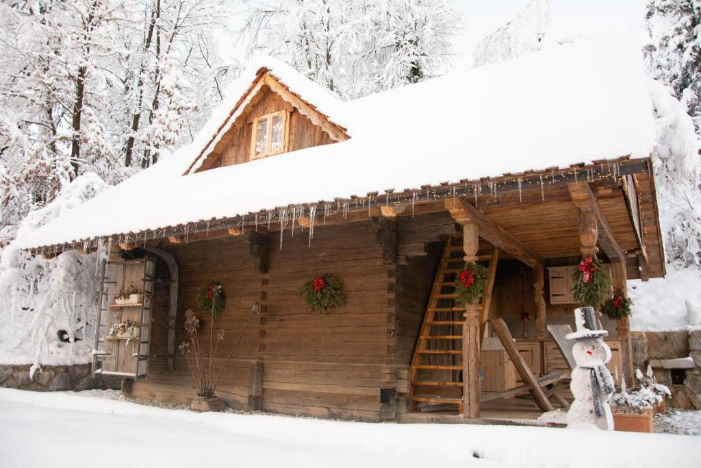 una cabaña de madera en la nieve con adornos navideños en Apartma kašča, en Domžale