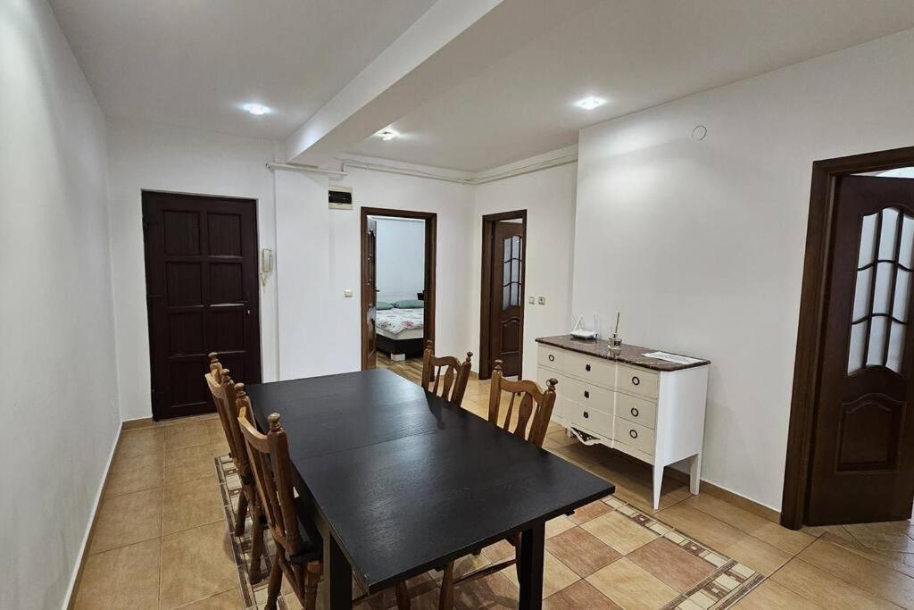 ein Esszimmer mit einem schwarzen Tisch und Stühlen in der Unterkunft Radauti Residence 1P in Rădăuţi