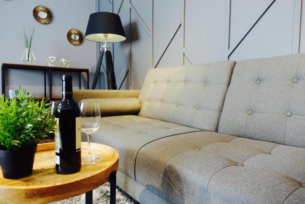 a couch with a bottle of wine on a table at Apartament LOFT-Grupa PlażoweLove in Krynica Morska