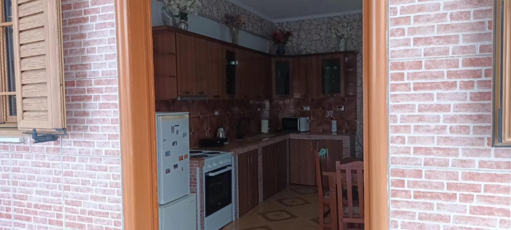 a kitchen with wooden cabinets and a brick wall at Artan apartment in Vlorë