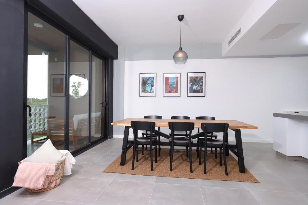 a dining room with a wooden table and black chairs at Lumina at Flats Punta Cana Village in Punta Cana