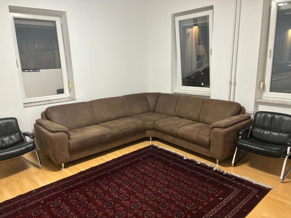 sala de estar con sofá marrón y 2 sillas en Neu-Isenburg 2 x Zimmerwohnung DG, en Neu Isenburg