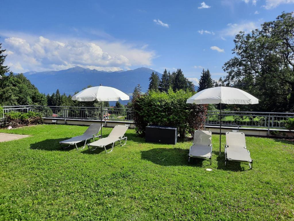 a group of chairs and umbrellas on the grass at Sweet Cherry - Boutique &amp; Guesthouse Tyrol in Innsbruck