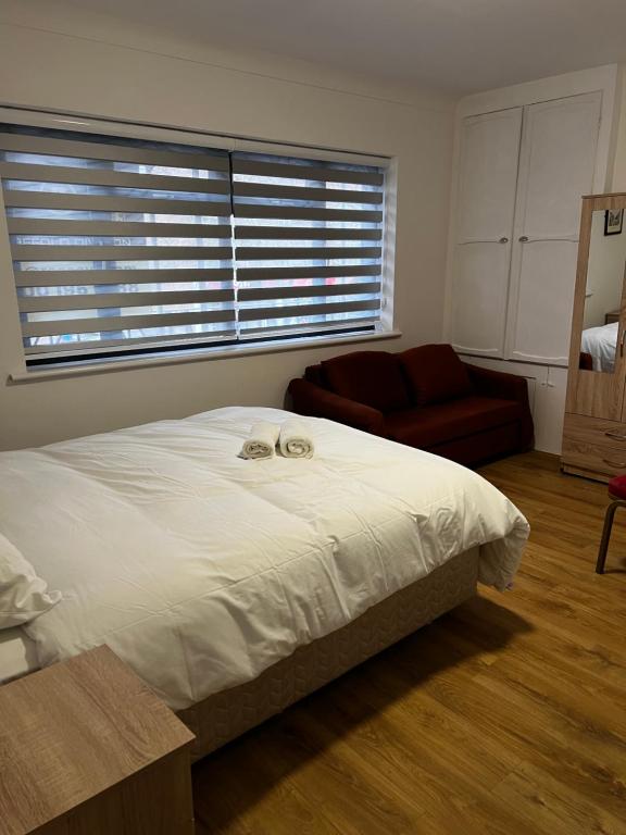 a bedroom with a bed and a couch and a window at The Barrington Hotel in New Barnet