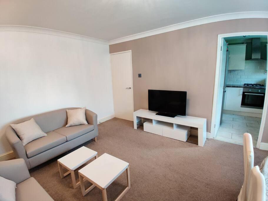 a living room with a couch and a tv at Cosy and modern two bedroom flat near Heathrow in Hayes