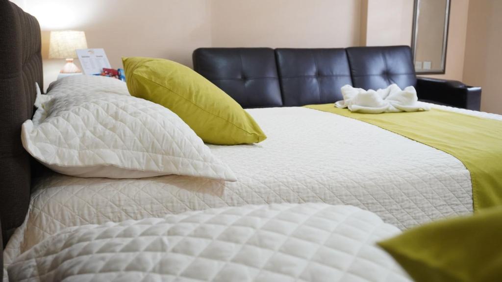 YORMARI HOTEL في مانتا: سرير بملاءات بيضاء ومخدات خضراء