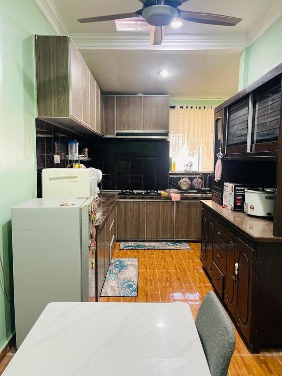 een keuken met houten kasten en een witte koelkast bij Mak kuntum homestay in Sungai Petani
