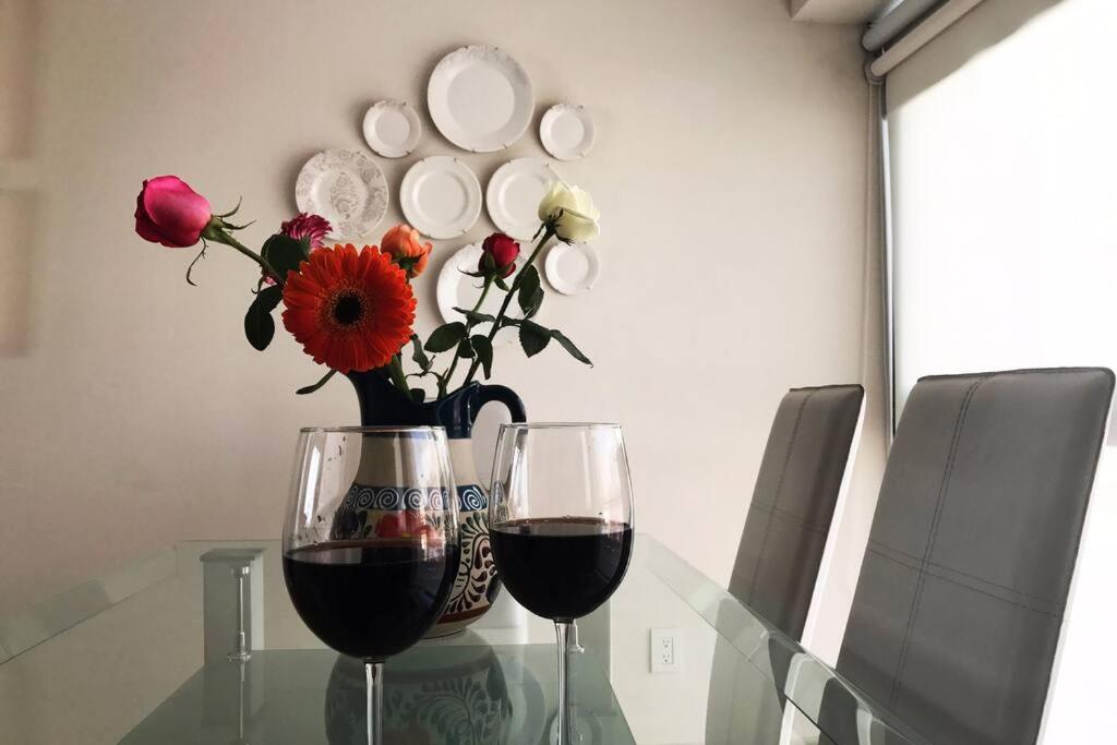 due bicchieri di vino e un vaso con fiori su un tavolo di vetro di Cerca de hospital infantil wtc centrico y seguro! a Città del Messico