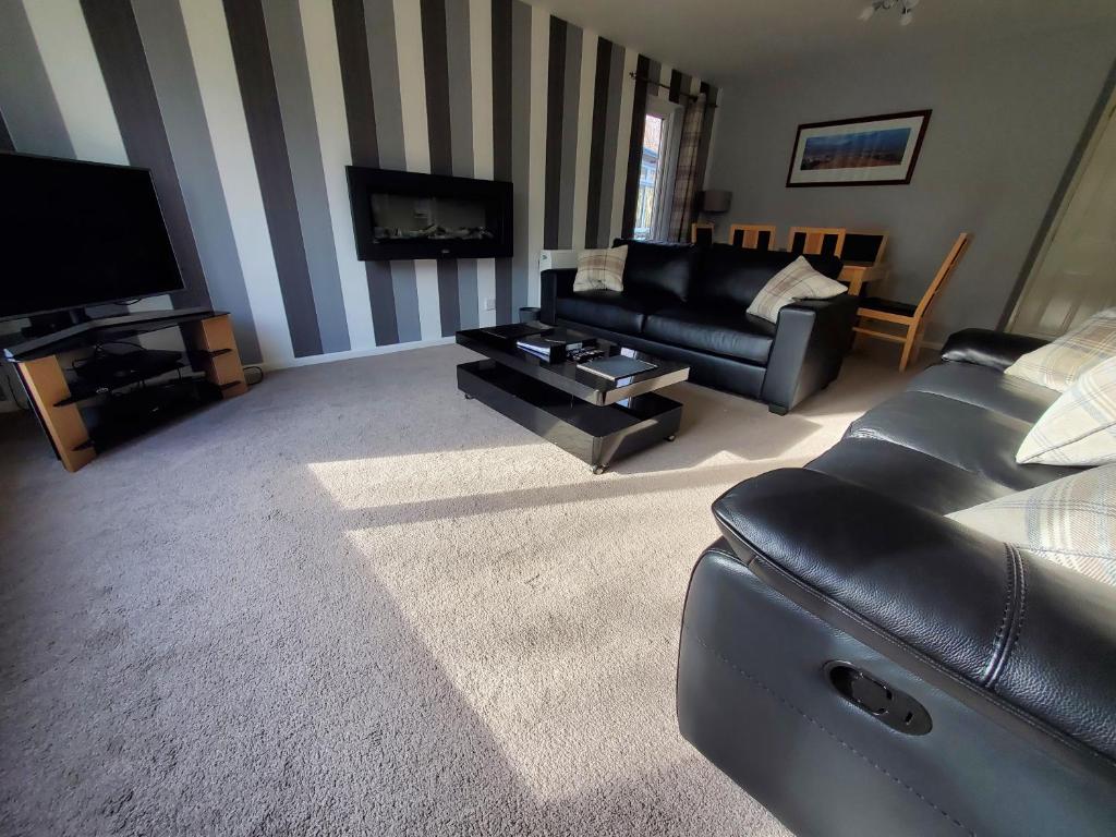 a living room with a couch and a tv at Aviemore Bungalow, Dalfaber in Aviemore