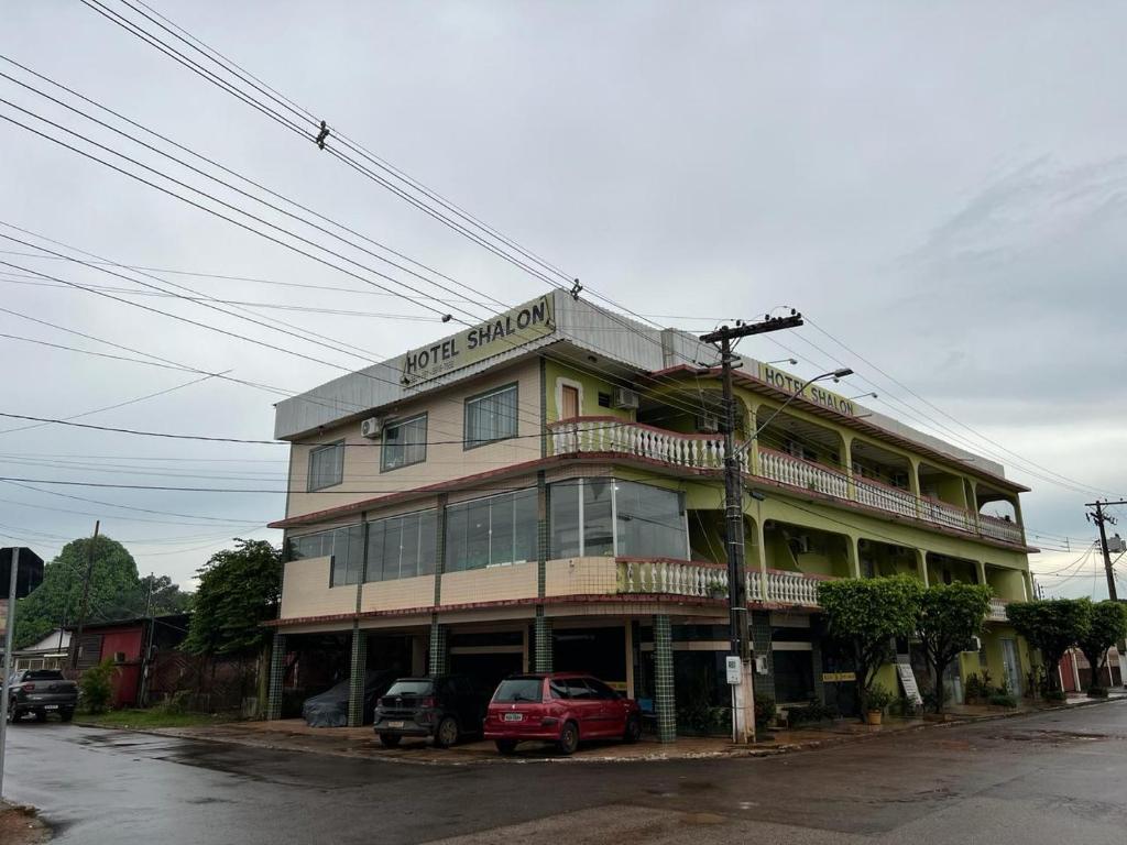 un grand bâtiment avec des voitures garées devant lui dans l'établissement Hotel Shalon, à Rio Branco