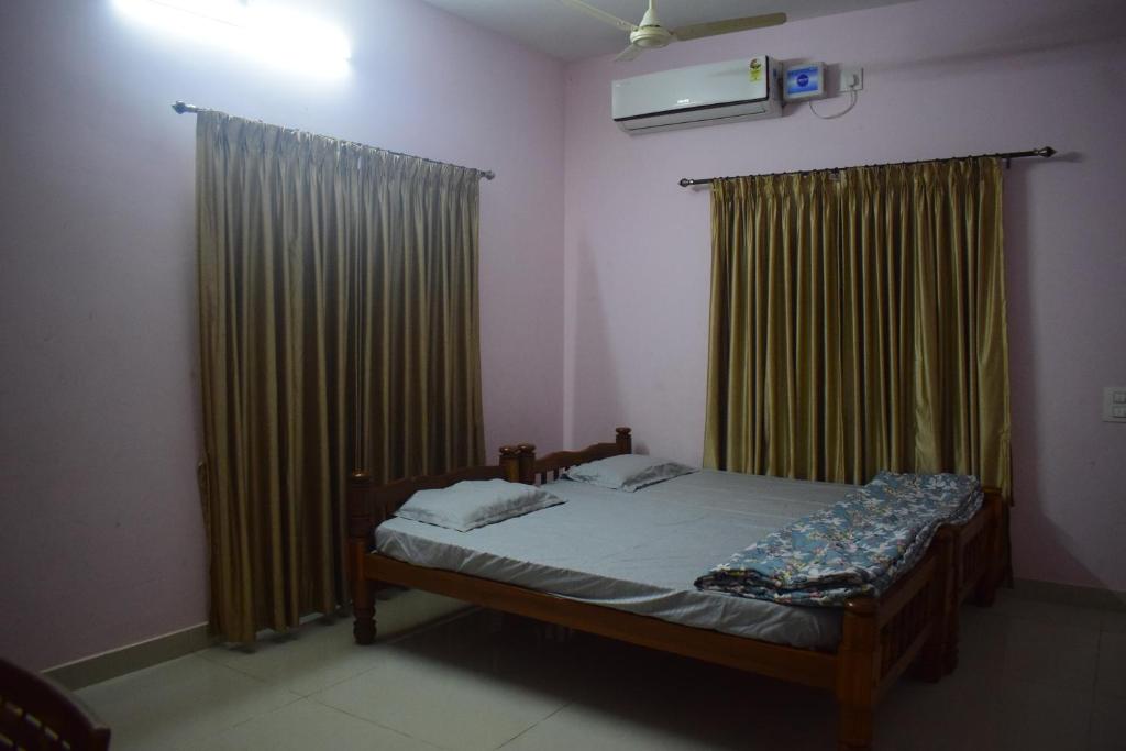 a bedroom with a bed and curtains and a tv at DELTA HOSPITALITY - sea faceing rooms with private beach in Kalyānpur