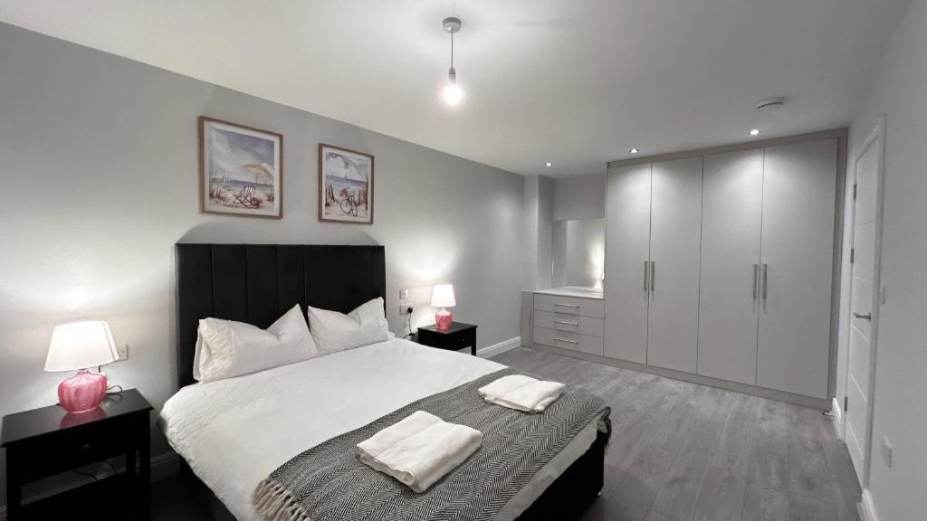 a bedroom with a large bed with two lamps and a cabinet at Spacious 4 Bedroom New-build N2 in Aldershot