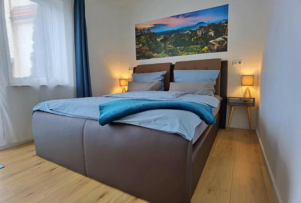 ein Schlafzimmer mit einem großen Bett mit blauer Bettwäsche in der Unterkunft Moderne Ferienwohnung im Herzen von Königstein in Königstein an der Elbe