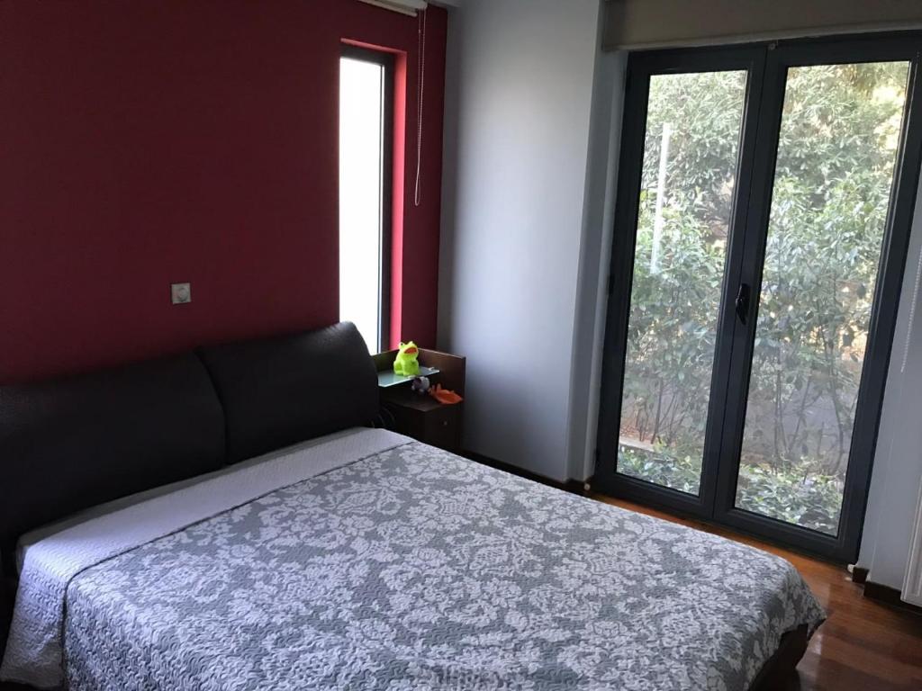 ein Schlafzimmer mit einem Bett und zwei großen Fenstern in der Unterkunft Mina’s Villa, 200m from the beach in Porto Rafti