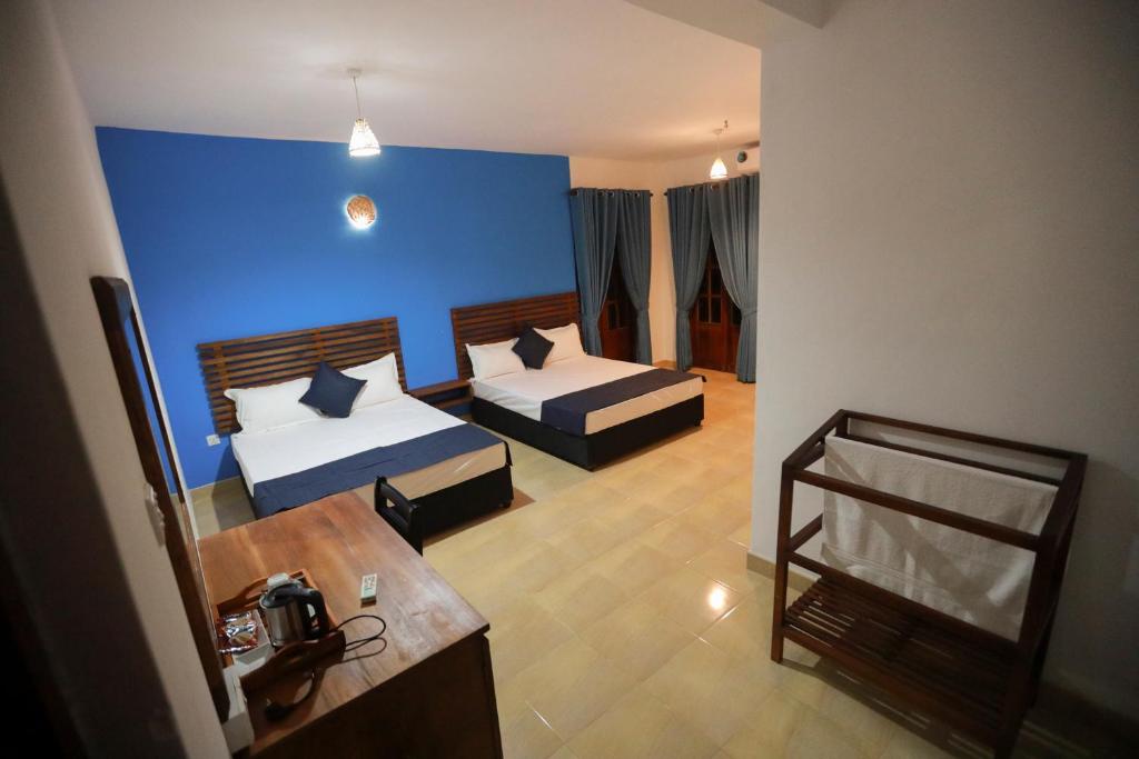 um quarto com 2 camas e uma parede azul em Stellar Inn em Peradeniya