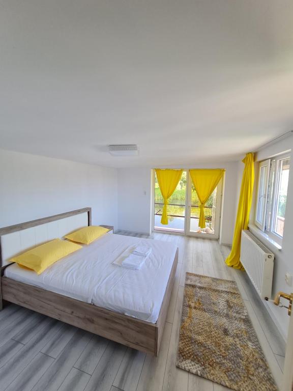 una camera da letto con un grande letto con tende gialle di Casa Egreta Alba a Dunavăţu de Jos