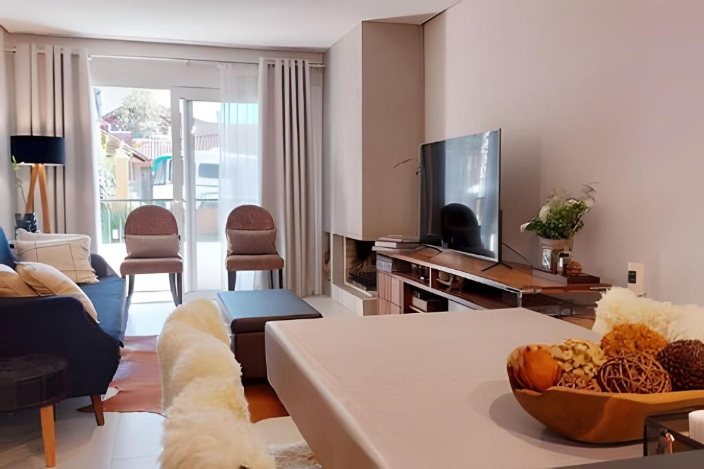 a living room with a couch and a tv at Apto Elegance Bairro Nobre, junto a Natureza in Canela