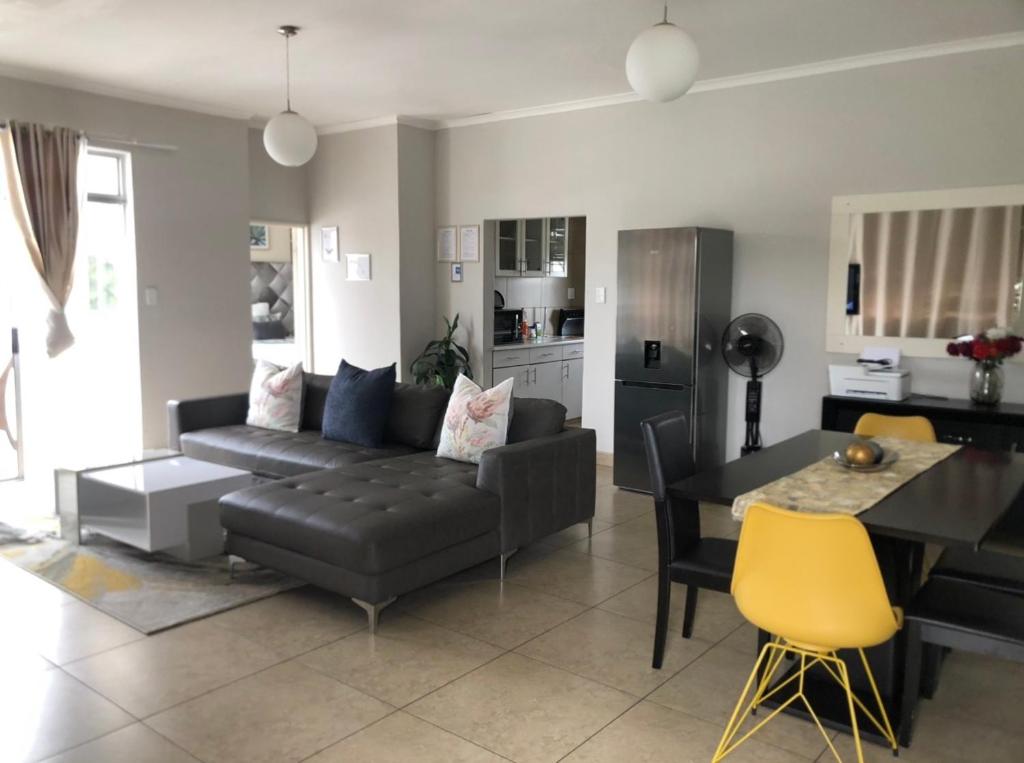 een woonkamer met een zwarte bank en een tafel bij Maerua Mall Luxe Accommodations 3rd Floor in Windhoek