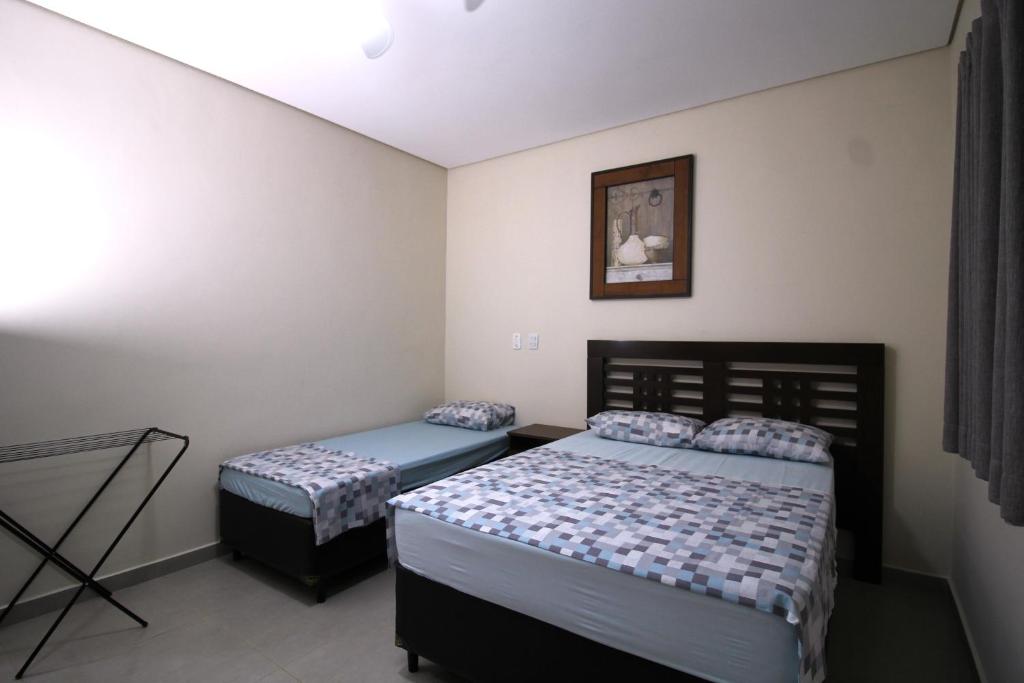 a bedroom with two beds and a picture on the wall at POUSADA JARDIM BOTANICO in Olímpia