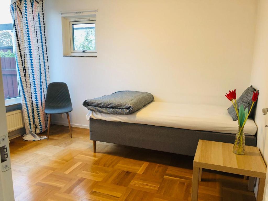 um pequeno quarto com uma cama e um vaso com uma flor sobre uma mesa em Home Stays-Private Rooms in a Villa Near City for families/Individuals em Estocolmo