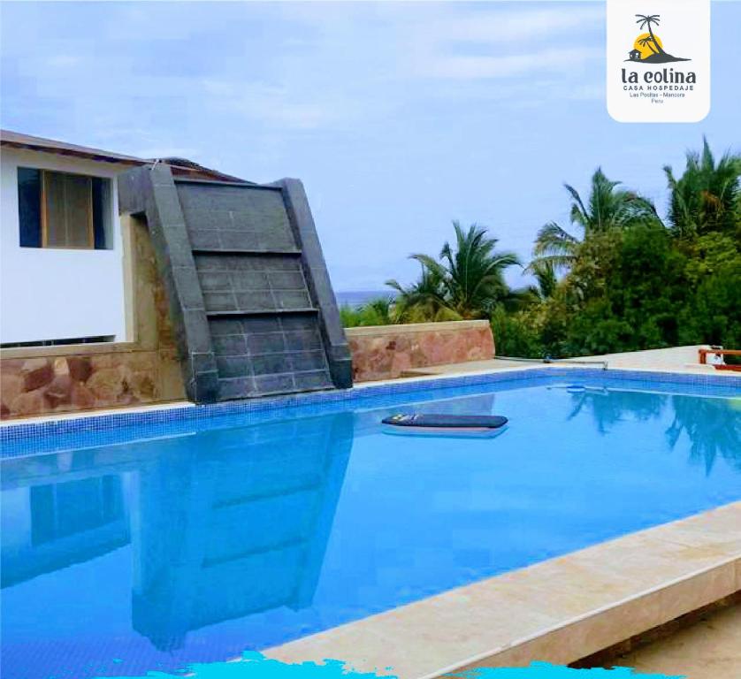 a large blue swimming pool with a chair next to it at LA COLINA Casa-Hospedaje in Máncora