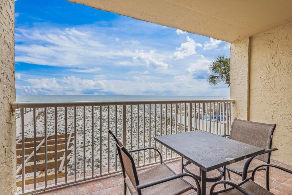 Una mesa y sillas en un balcón con vista a la playa. en Driftwood Towers 1G, en Gulf Shores