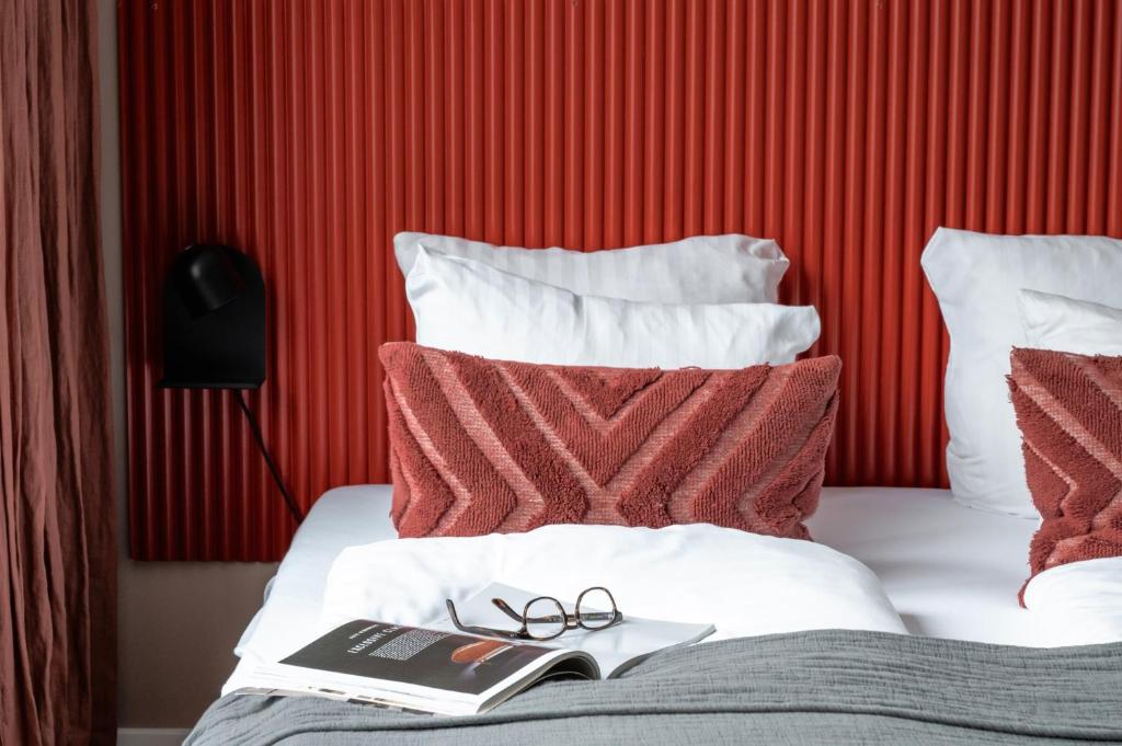 a pair of glasses and a book on a bed at The Lakes apartments by Daniel&Jacob's in Copenhagen