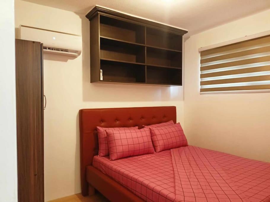 a bedroom with a red bed with pink pillows at Syv's 2Br & 1T/Bath Condo Oasis Behind SM Mall 411 in Davao City