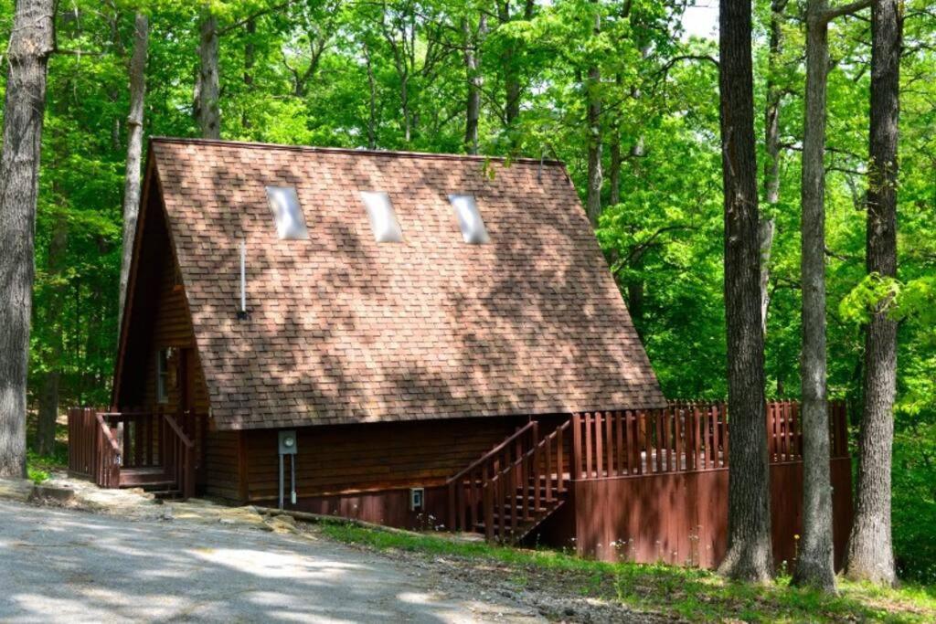 a house with a shingled roof in the woods at A-Frame Cabin #6 with Hot Tub on Patoka Lake in Southern Indiana in Seymour