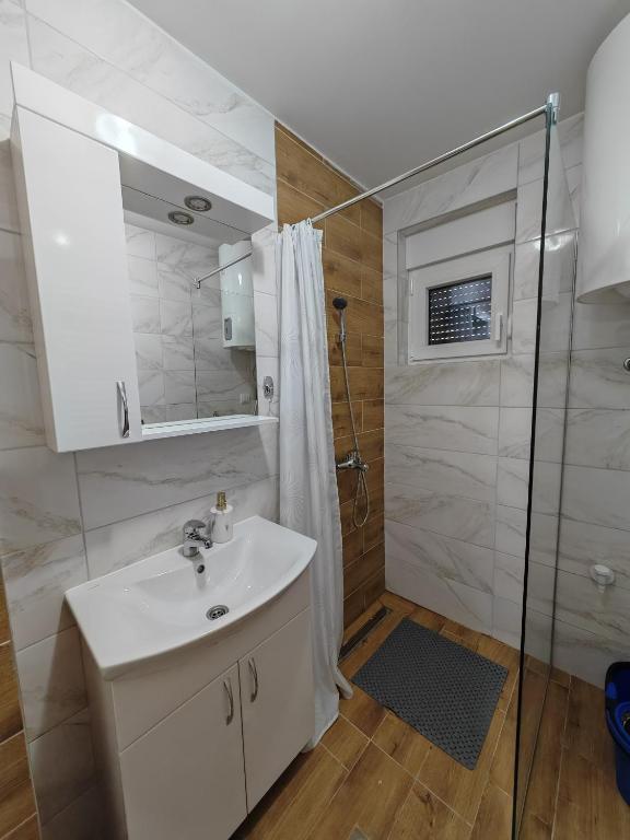 ein Badezimmer mit einem weißen Waschbecken und einer Dusche in der Unterkunft Apartman Monika 2 in Divčibare