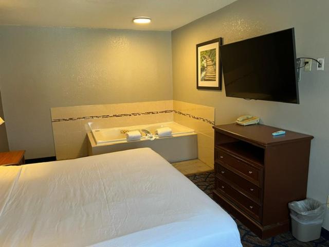 a bedroom with a bed and a tv and a tub at Baymont by Wyndham Waukesha in Waukesha
