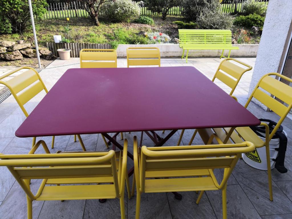 een paarse tafel met gele stoelen eromheen bij Chambre dans un écrin de verdure in Dommartin