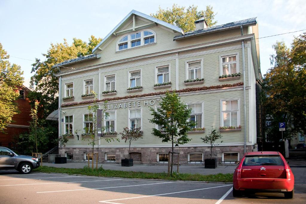 un'auto rossa parcheggiata di fronte a un edificio bianco di Elizabete Design Hotel a Riga