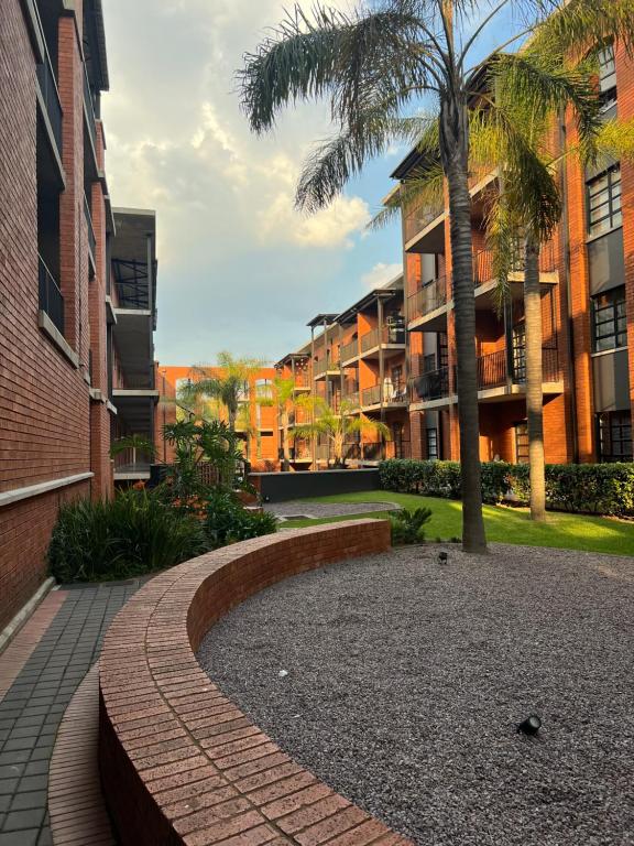 a walkway in a courtyard with palm trees and buildings at The Fitz Apartment in Johannesburg