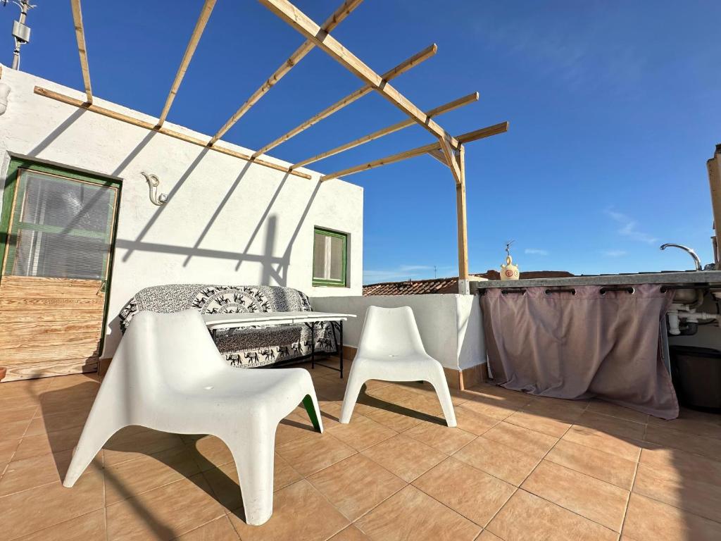 eine Terrasse mit einem Tisch und 2 weißen Stühlen in der Unterkunft Apartamento con terraza Delta Slow in Deltebre
