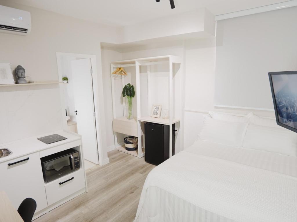 a white bedroom with a bed and a tv at Apê Metrô Paraíso in Sao Paulo