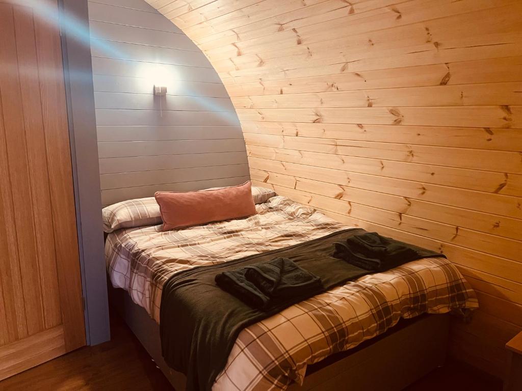 a small bed in a room with a wooden wall at Hidden Hut - Aros View - Tobermory in Tobermory