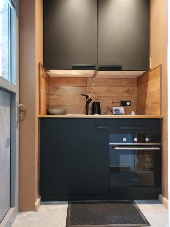 a kitchen with black cabinets and a sink at Le rustiques Moderne de la Raquette in Mons