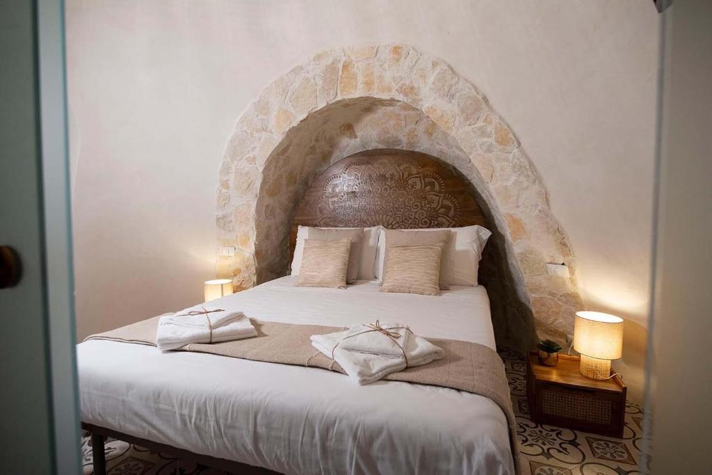 een slaapkamer met een groot bed met een stenen hoofdeinde bij Trullo Imperiale in Cisternino