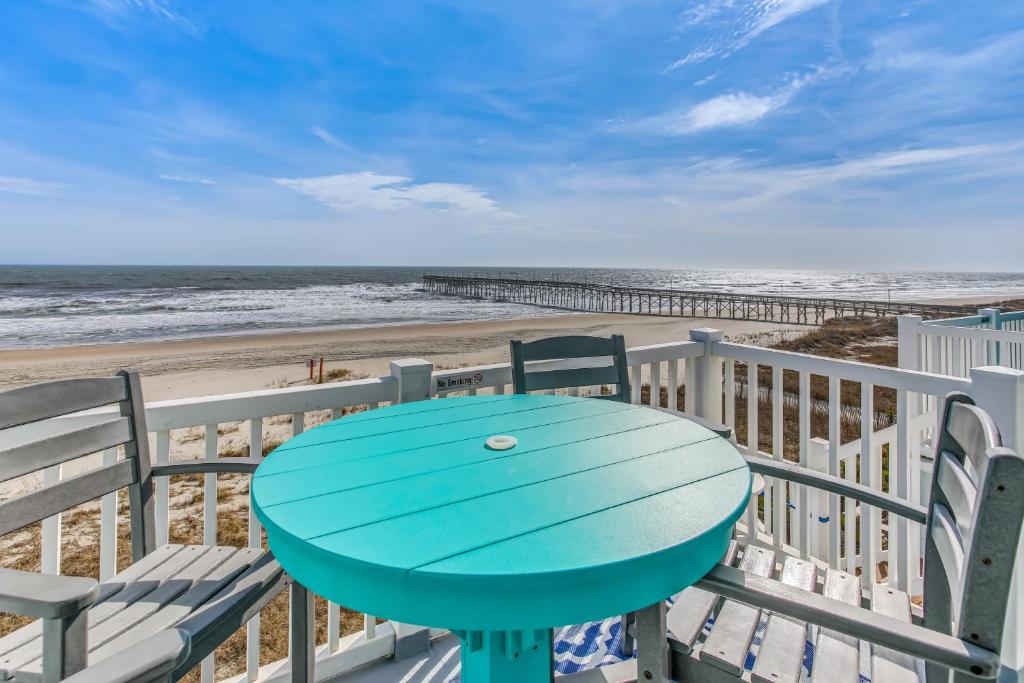 einen blauen Tisch auf einem Balkon mit Strand in der Unterkunft Salt and Light Oceanfront Condo with Pool and Elevator in Ocean Isle Beach